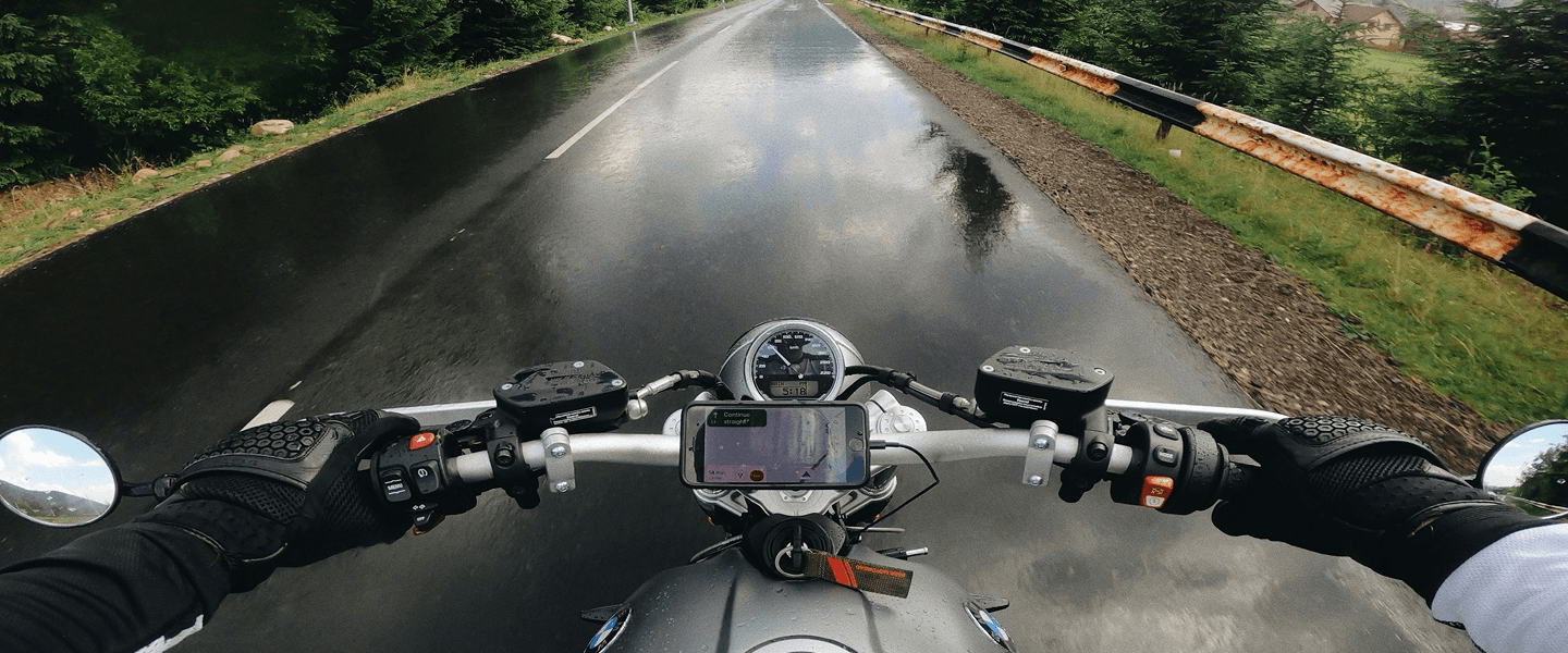 Rider's-eye view of a motorcycle on a wet forest road, captured on a MyFitSpark action camera